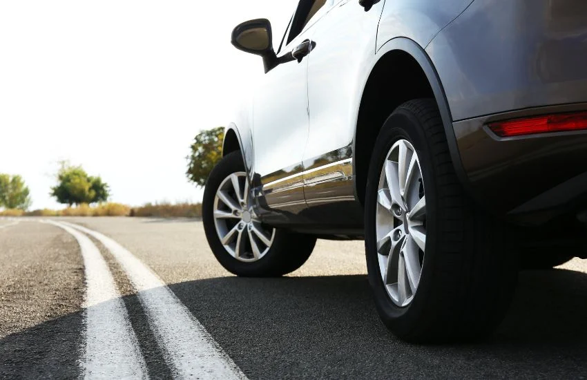 SUV gris acelerando en carretera secundaria; mostrando aerodinámica y rozamiento, factores que influyen en la potencia del coche.